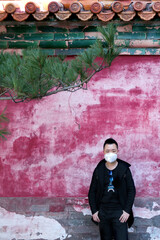 Handsome guy wearing a mask in front of the red wall in Beijing Summer Palace