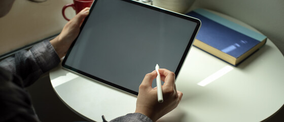 Female freelancer working with digital tablet with stylus pen on coffee table at home