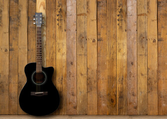 A black acoustic guitar on a wooden floor