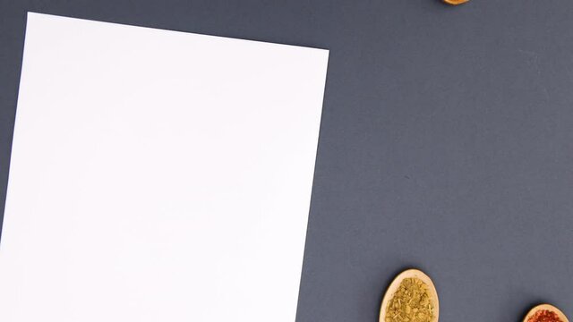 Wooden spoons with spices appear next to white paper for recipe - Stop motion 