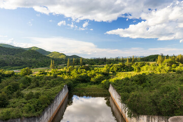 Lake dam water reservoir with mountain forest in beautiful clouds and beautiful blue sky, reservoir for innovations in agro-industry, irrigation.