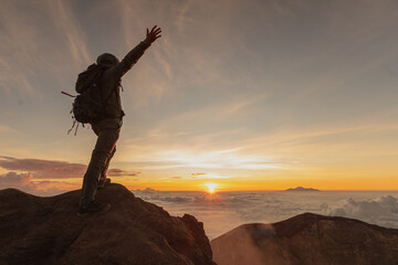 the man backpacker on top of the vulcano agung meets the sunrise. crater view. Higher than clouds....