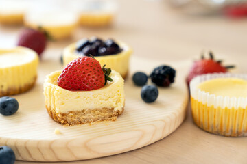 Mini cheesecake with blueberry, blackberry and strawberry ready to be served on wooden table