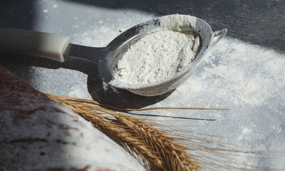 Bread with flour and spikelets of wheaton gray background. Fabric, cooking.