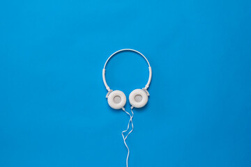 Beautiful white headphones with a wire on a blue background.