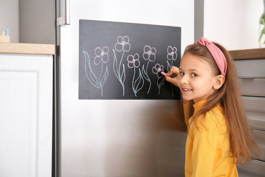 Little Girl Drawing On Chalkboard In Kitchen