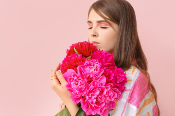 Young woman with beautiful peony flowers on color background