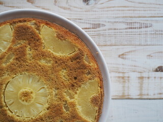 Close up.Confectionery background. Round sponge cake with pineapple on a white wooden table. Healthy natural food.