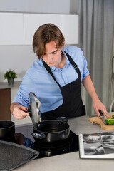 Handsome young man checking a pot at a kitchen