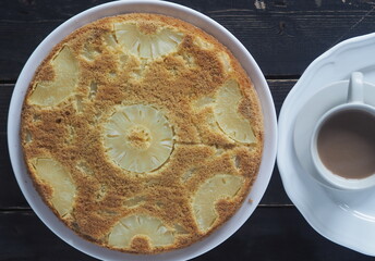 Sponge cake with pineapple on a dark wooden table.Home cooking.