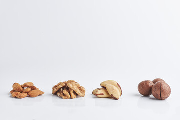 almonds, walnuts, macadamia, Brazilian nut on a white background. a few handfuls of raw nuts. copy space for text.