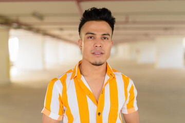 Face of young handsome multi ethnic man at modern building