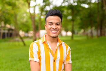 Fototapeta premium Happy young handsome multi ethnic man smiling at the park outdoors