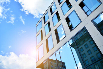 Facade texture of a glass mirrored office building. Fragment of the facade. Bottom view of modern skyscrapers in business district in evening light at sunset with lens flare filter effect.