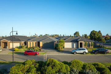 Elevated view of modern suburban homes in an Australian suburb with family cars parked on side of...