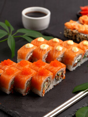 Sushi rolls on colored plates on a black background. A look from above.