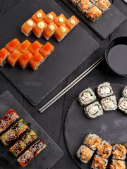 Sushi rolls on colored plates on a black background. A look from above.