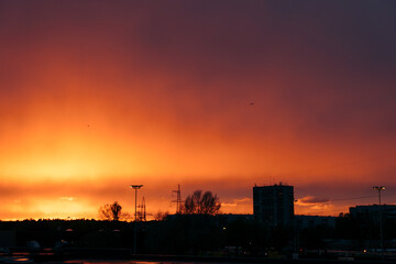 Golden fire sunset with clouds in Riga with silhouette of the buildings trees