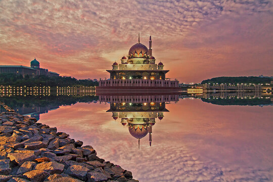 Dramatic sunrise view over putrajaya with reflection of Putra Mosque and unique cloud formation