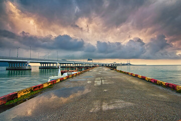 Landscape view of a jetty with water pots reflecting bad weather clouds with penang second bridge as background