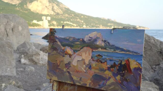 Art therapy in nature. Artist painting image of the sea and cliffs, landscape, seascape and summer sunset. The Fast-Track to Healing And Rehabilitation. Physical distance, social distance