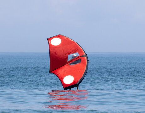Wing foil in the Pacific Ocean Japan. A man is using an Inflatable wing with a board in the ocean, it is a new sport. Its is red and the ocean blue.