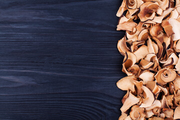 Edible dried mushrooms border black wooden background close up top view, dry boletus edulis dark wood backdrop frame, brown cap boletus, penny bun, cep, porcino, porcini, white fungus, text copy space