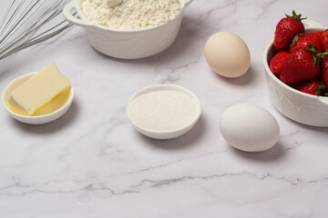 ingredients for baking strawberry muffins on white.