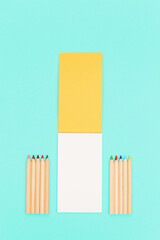 Top view of colored pencils and open sketch pad for creativity. Set of wooden multicolored pencils. Work space for drawing.