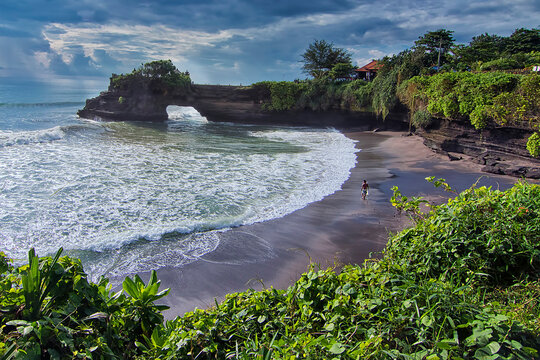 Great landscape shot of a beach in Tanah Lot Bali where a surfer getting ready to surf