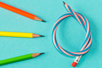 Simple pencils and flexible pencil on a blue background. Close up. Selective focus.