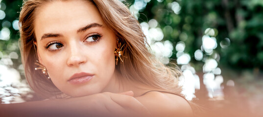 Enjoy nature. Close-up portrait of a young beautiful caucasian woman with hazel eyes and light brown hair looking aside with her piercing eyes while posing outdoors. Beauty concept. Horizontal shot