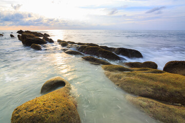 Amazing twilight Sunset seascape with sea wave hitting the green moss