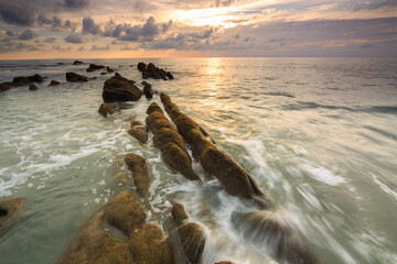 Amazing twilight Sunset seascape with sea wave hitting the green moss