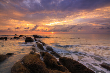 Amazing twilight Sunset seascape with sea wave hitting the green moss