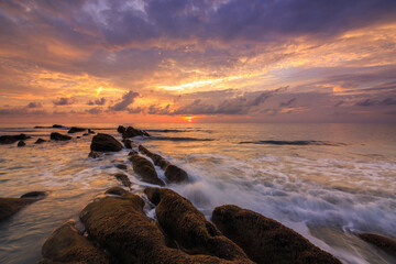 Amazing twilight Sunset seascape with sea wave hitting the green moss