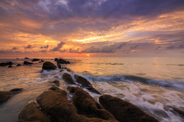 Amazing twilight Sunset seascape with sea wave hitting the green moss