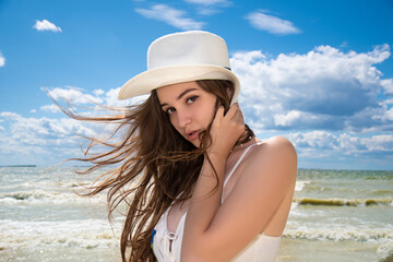 Closeup portrait of beautiful young woman in white hat. Girl relaxing. Summer lifestyle