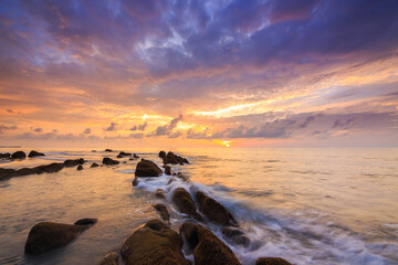 Amazing twilight Sunset seascape with sea wave hitting the green moss
