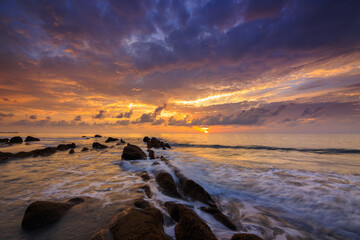 Amazing twilight Sunset seascape with sea wave hitting the green moss