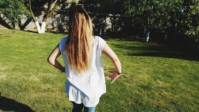 Caucasian girl dancing bachata in the sun on green grass in summer