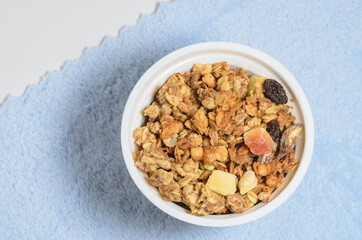Muesli in a round cup on a blue fluffy background. Added to milk or yogurt for breakfast. Selective focus.