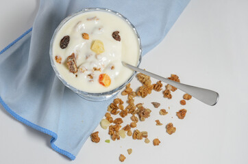 Yogurt in a beautiful glass bowl next to a box of granola and a spoon.
