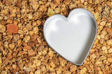 A baking dish in the form of a heart inside a muesli surface.