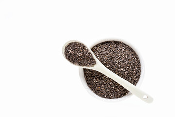 Chia seeds ( Salvia hispanica ) in white ceramic bowl and spoon isolated on white background. Healthy food or superfood and supplement concept. Flat lay.