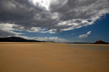 Fototapeta na wymiar Gran playa vacía con marismas y nubes de tormenta
