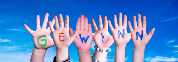 Children Hands Building Colorful German Word Gewinn Means Prize. Blue Sky As Background