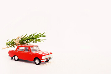 Red retro Christmas tree delivery toy car on a white background in winter with snow. New Years is soon.