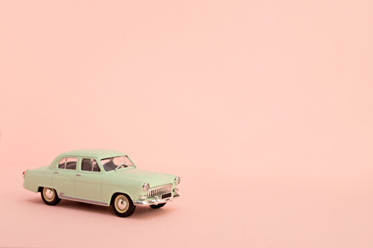 Green retro toy car delivering flowers and gifts on a pink background. Copy space. © Анна Александровна Х