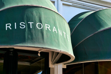 Closeup of green exterior window awnings outside an italian restaurant with word ristorante on it.